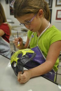 Casey Cramer paints a mask at a previous Kemper Kids art camp.