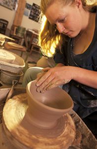 A student tries her hand at the pottery wheel.