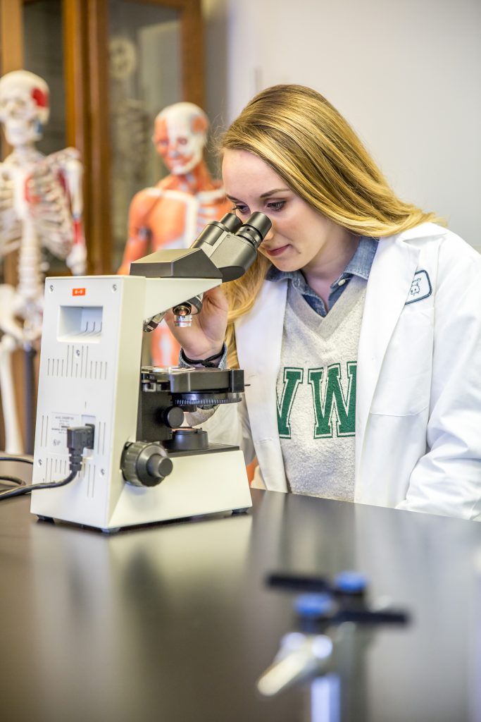 Ari Arnold looking into a microscope