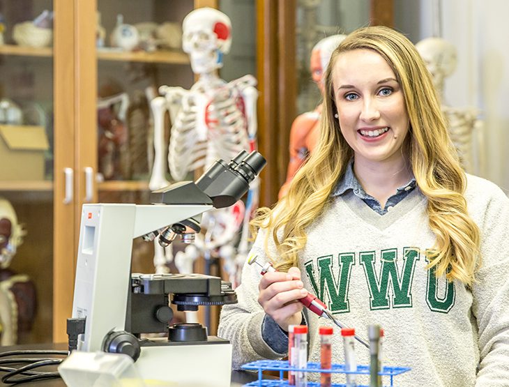 Ari Arnold posing with biology lab equipment