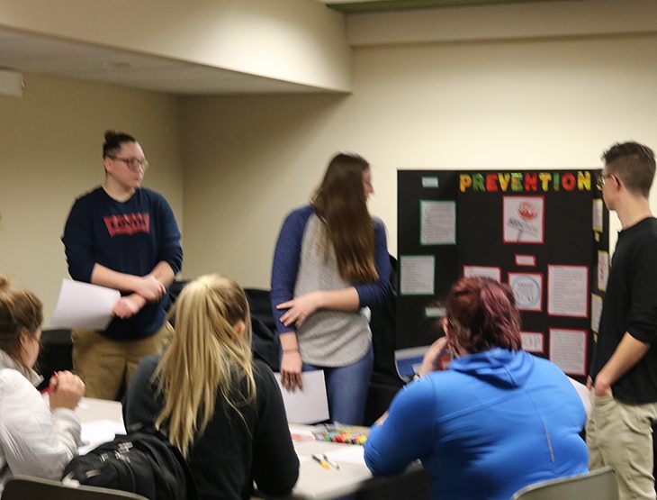 Students gathered around a poster board presentation