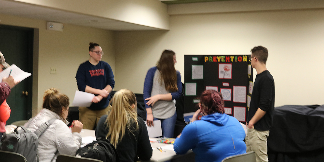 Students gathered around a poster board presentation