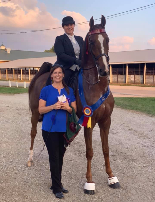 Sarah Track standing next to Alix Polydoros riding "Loaded Question"