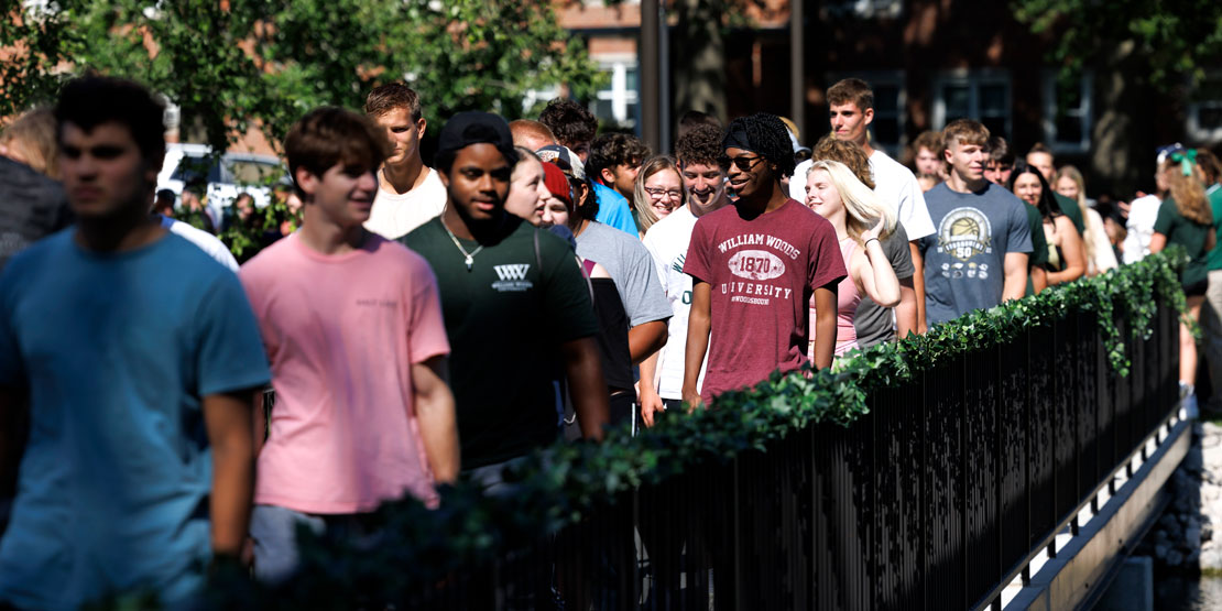 students walk across the senior lake bridge during the Ivy Ceremony