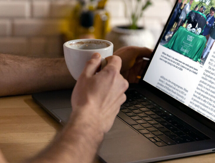 Person reading the Chronicle of Higher Education article online with a cup of coffee.