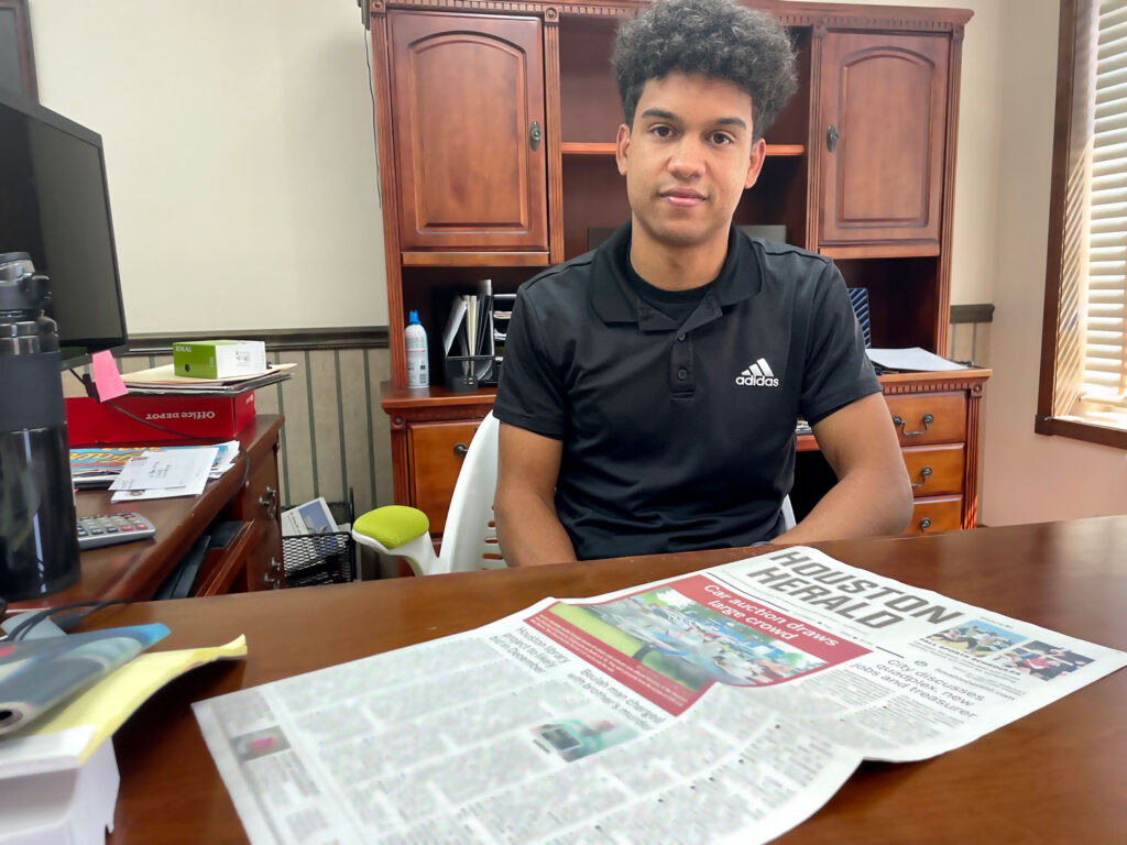 Isaiah Buse sitting at his desk at the Houston Herald newspaper