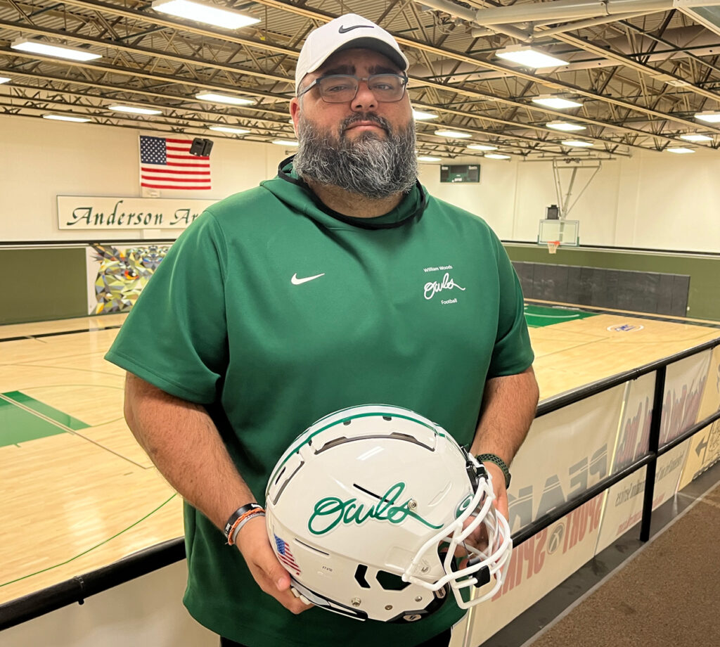 Julian Mendez in Anderson Arena on William Woods University campus holding the new Owls football helmet