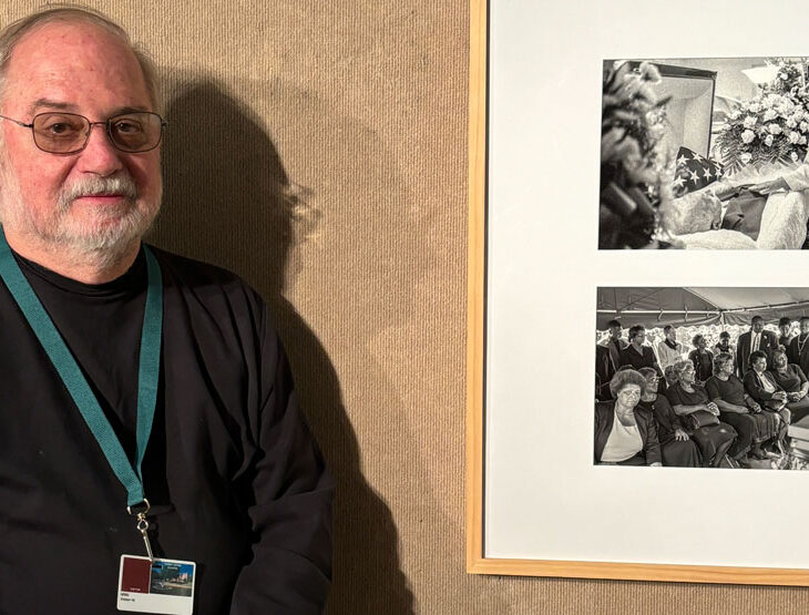 Photographer Richard Orton stands next to his pieces in the art gallery