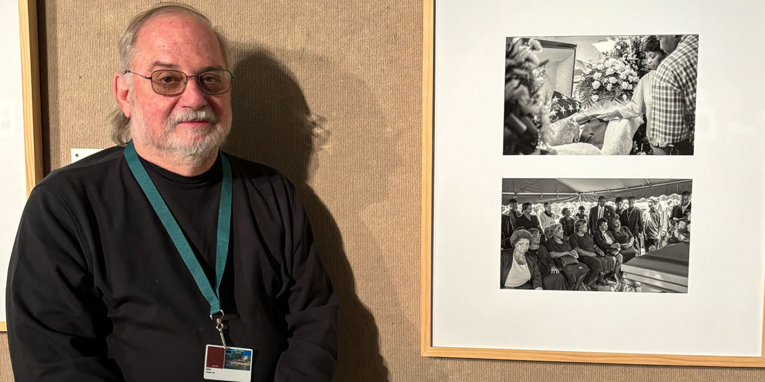 Photographer Richard Orton stands next to his pieces in the art gallery